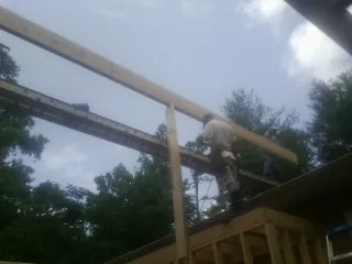 Carpenter setting a ridge beam over a new addition frame — Ice Dam Removal by Roofing Brothers in Kaplan