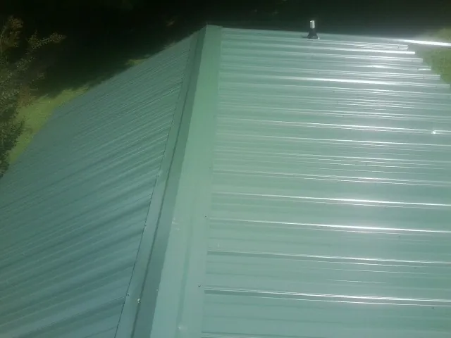 New green metal panels meeting at the ridge of a roof — Flat Roof Repair work by our crew in Kaplan