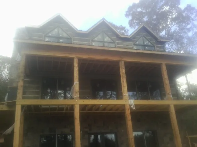Dormers and porch framing on a large log home under construction — Roof Coating work by our crew in Kaplan