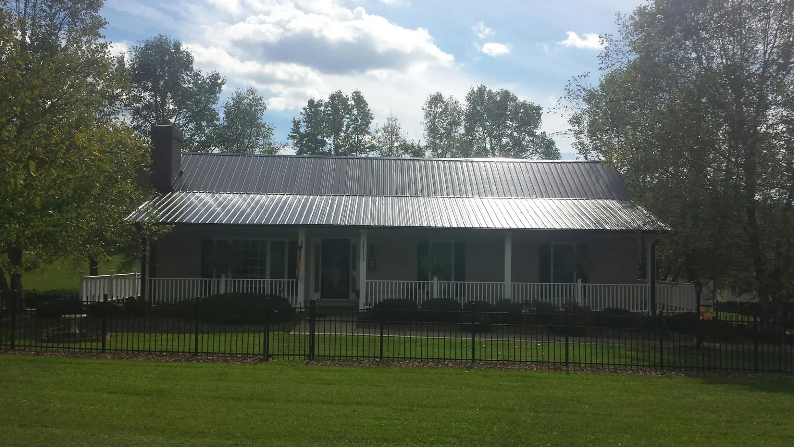 Gray metal roof on a brick ranch with a full width front porch — Gutter Guard Installation work by our crew in Kaplan
