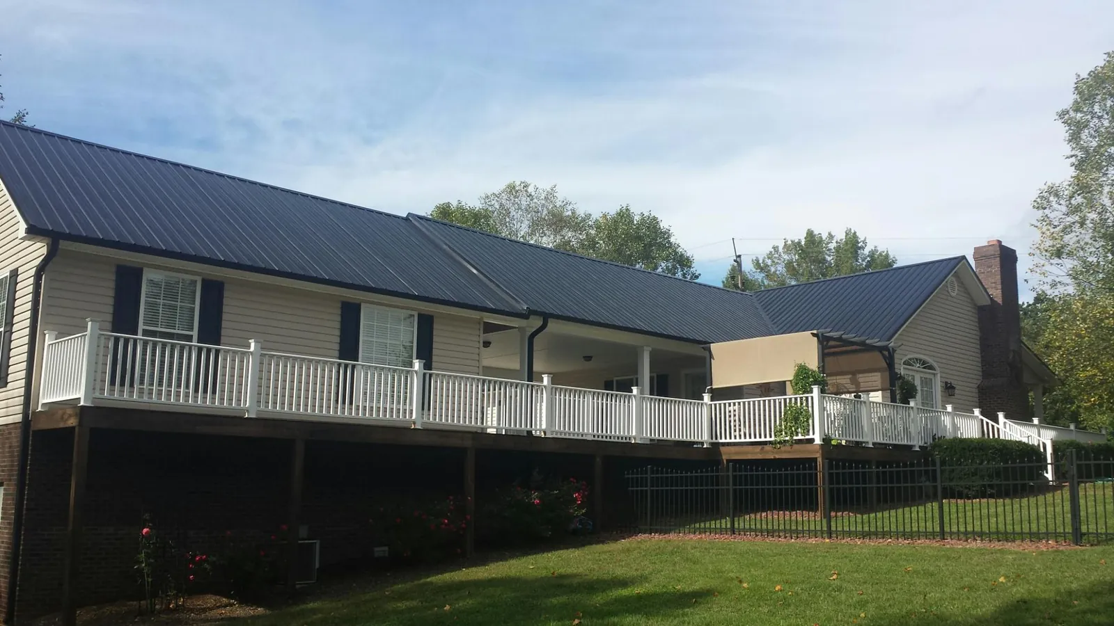 Black metal roof above a long white railed deck on a hillside home in Kaplan