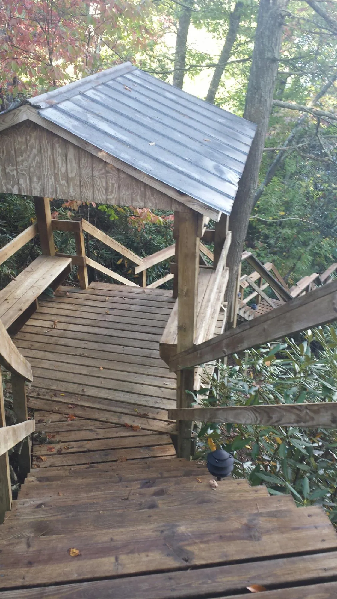 Metal roofed shelter over wooden steps on a wooded walkway — Skylight Repair & Installation work by our crew in Kaplan